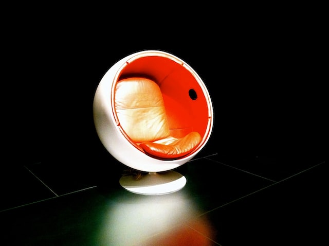 En klassisk vit Egg Chair med orangea dynor.